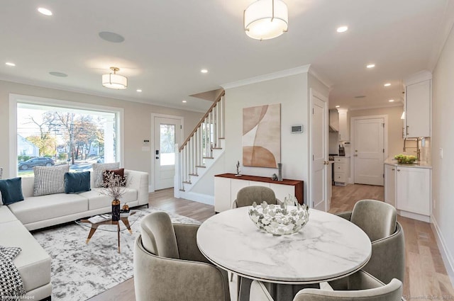 living room featuring light wood-type flooring, crown molding, and a healthy amount of sunlight