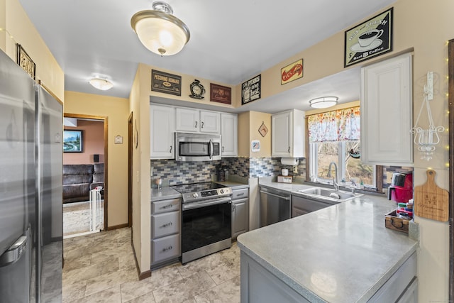 kitchen with kitchen peninsula, backsplash, stainless steel appliances, sink, and white cabinets