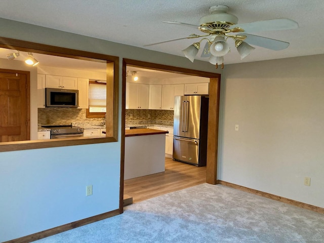 kitchen featuring backsplash, ceiling fan, white cabinetry, and stainless steel appliances