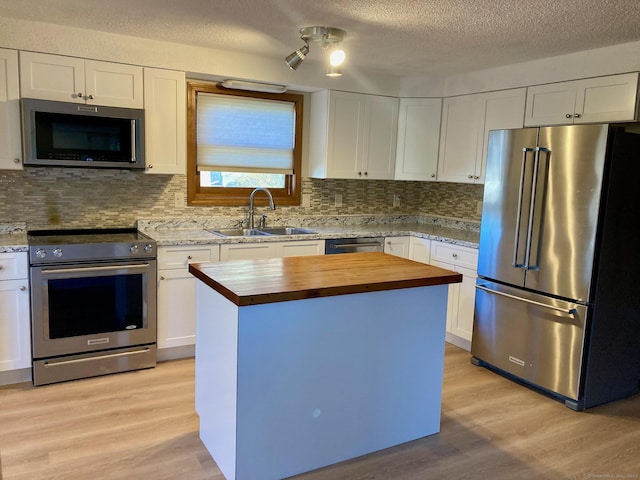 kitchen featuring a center island, white cabinets, sink, light wood-type flooring, and stainless steel appliances