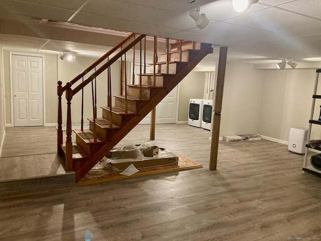 basement featuring wood-type flooring, a drop ceiling, and washer and clothes dryer