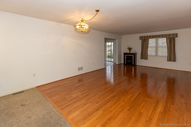 unfurnished living room with wood-type flooring and an inviting chandelier