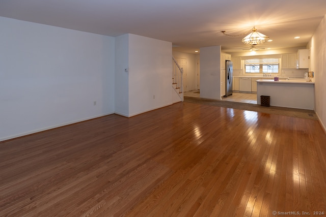 unfurnished living room with an inviting chandelier and light hardwood / wood-style flooring