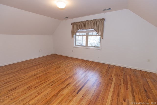 additional living space featuring lofted ceiling and light wood-type flooring