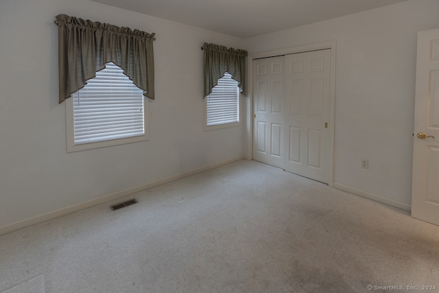 unfurnished bedroom featuring light colored carpet and a closet