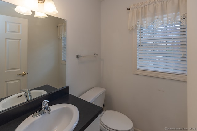 bathroom with vanity, toilet, and a notable chandelier