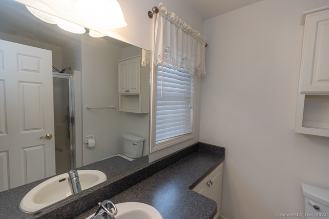 bathroom with toilet, a shower with door, and sink