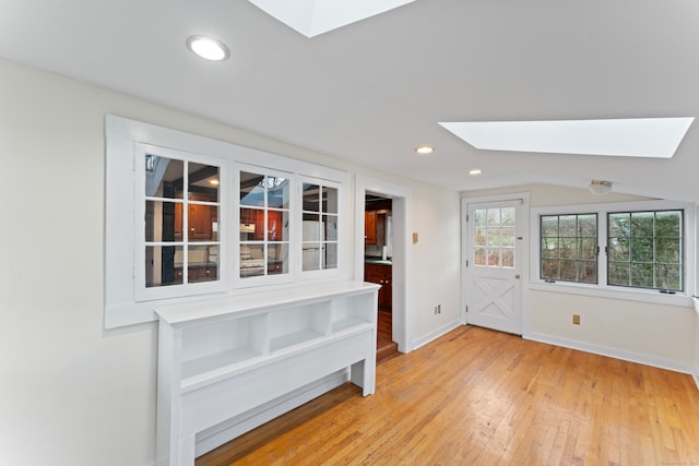 interior space featuring vaulted ceiling with skylight and light wood-type flooring