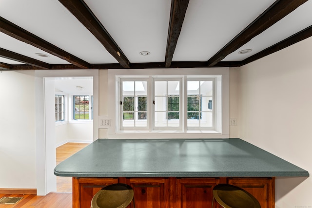 dining room featuring beam ceiling and light hardwood / wood-style flooring