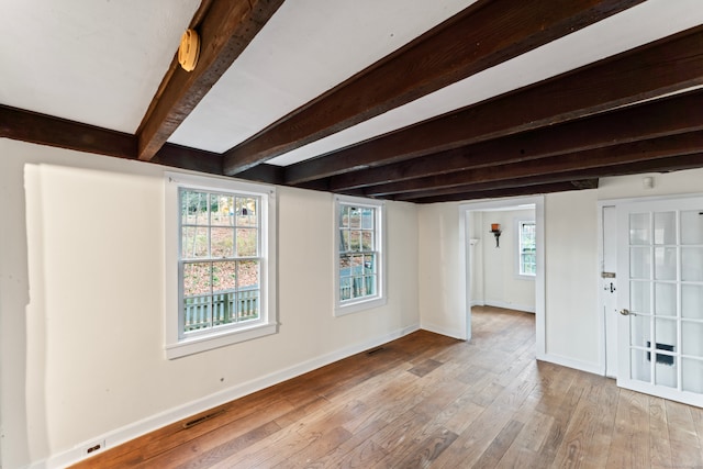 spare room with beamed ceiling and light hardwood / wood-style flooring