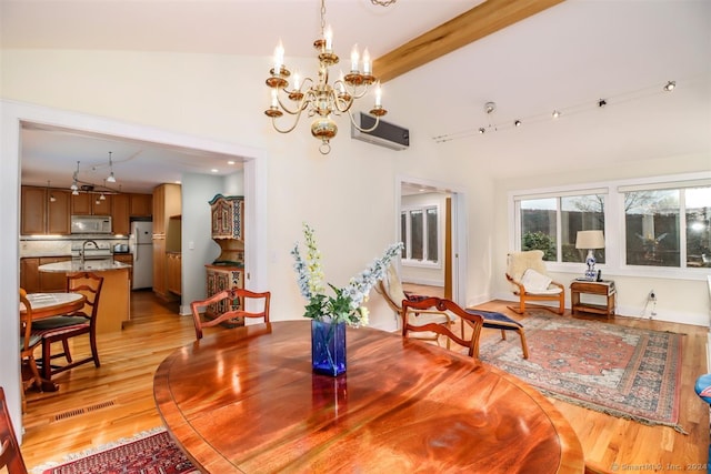 dining area with high vaulted ceiling, an AC wall unit, a chandelier, and light wood-type flooring