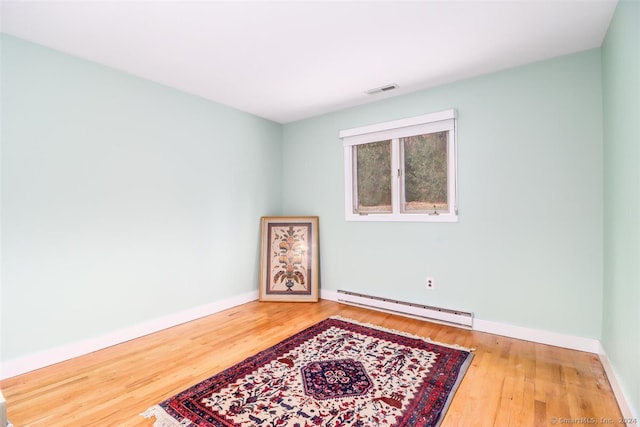 empty room with wood-type flooring and a baseboard radiator