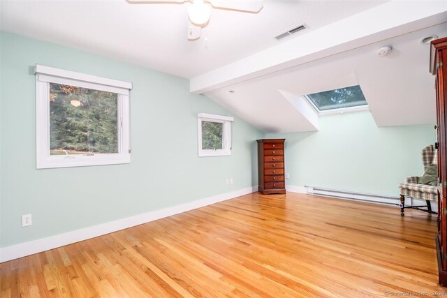 additional living space with wood-type flooring, a wealth of natural light, and baseboard heating