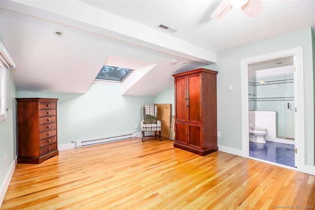 additional living space with light hardwood / wood-style floors, baseboard heating, a skylight, and ceiling fan