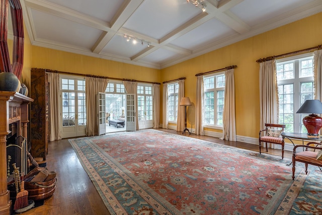 interior space with a fireplace with raised hearth, coffered ceiling, wood finished floors, french doors, and beamed ceiling