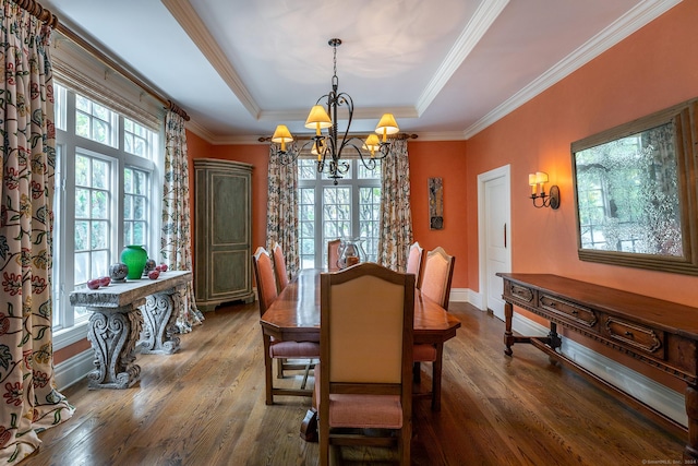 dining space featuring a tray ceiling, crown molding, an inviting chandelier, baseboards, and hardwood / wood-style flooring