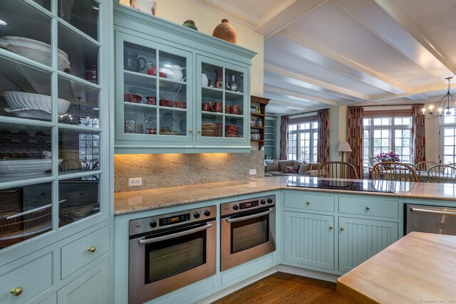 kitchen featuring a chandelier, stainless steel appliances, dark wood-style floors, beamed ceiling, and glass insert cabinets