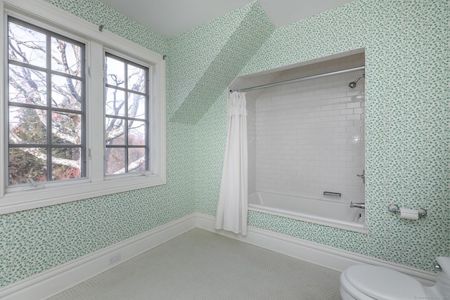 bathroom with toilet, wallpapered walls, a wealth of natural light, and shower / tub combo with curtain