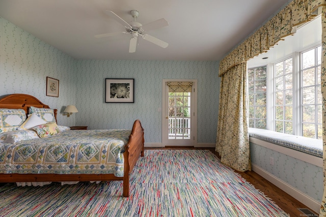 bedroom featuring baseboards, wood finished floors, visible vents, and wallpapered walls