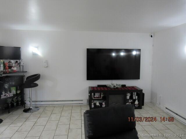 living room with light tile patterned floors, a baseboard heating unit, and a baseboard radiator