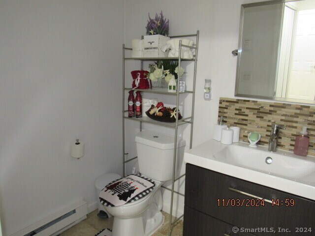 bathroom featuring vanity, toilet, decorative backsplash, and a baseboard radiator