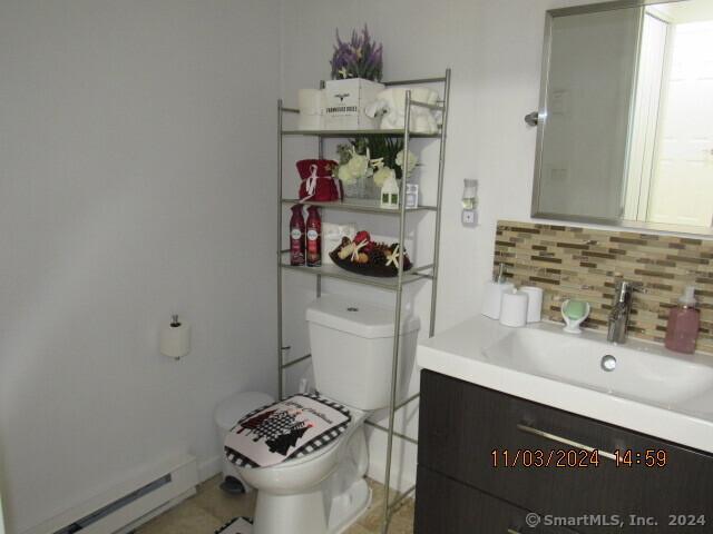 bathroom with tasteful backsplash, toilet, vanity, and a baseboard radiator