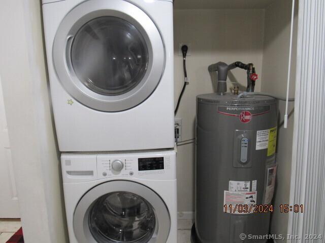 clothes washing area with laundry area, water heater, and stacked washer / dryer