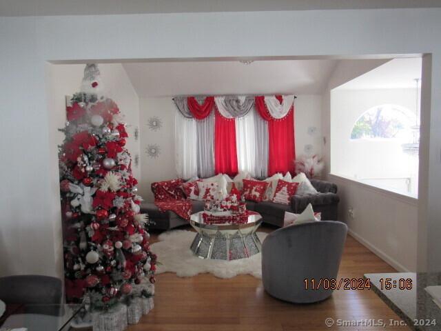 living area with lofted ceiling, wood finished floors, and baseboards