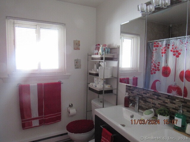 bathroom with vanity, toilet, walk in shower, and baseboard heating