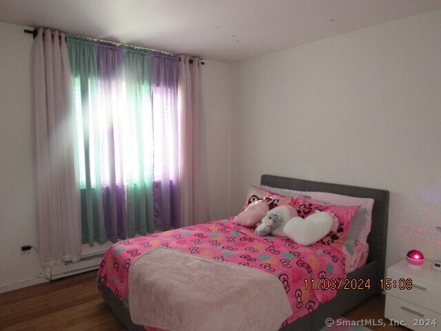 bedroom featuring a baseboard heating unit and wood-type flooring