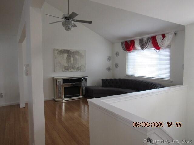 living room with a fireplace, wood finished floors, ceiling fan, and vaulted ceiling