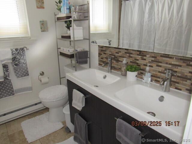 bathroom with a baseboard radiator, toilet, tasteful backsplash, and a sink