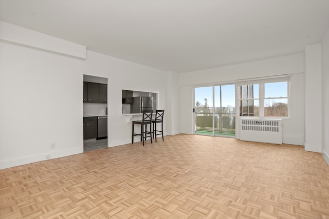 unfurnished living room featuring light parquet flooring and radiator