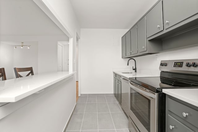 kitchen featuring kitchen peninsula, a kitchen bar, stainless steel electric range oven, light tile patterned flooring, and sink