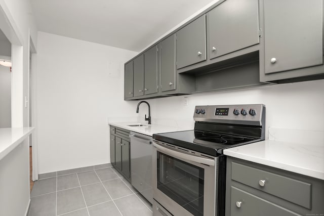 kitchen featuring sink, appliances with stainless steel finishes, gray cabinetry, and light tile patterned flooring