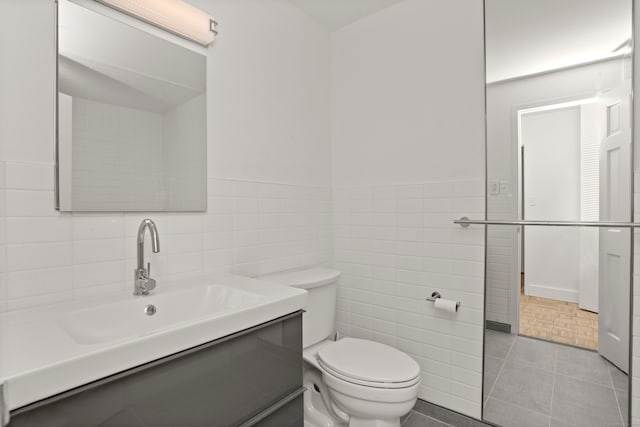 bathroom featuring vanity, toilet, tile walls, and tile patterned flooring