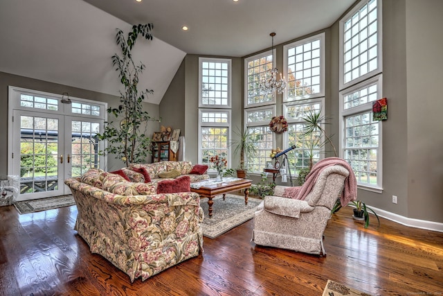 living room featuring french doors, a towering ceiling, dark hardwood / wood-style floors, and a notable chandelier