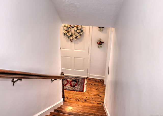 staircase featuring hardwood / wood-style floors and a textured ceiling