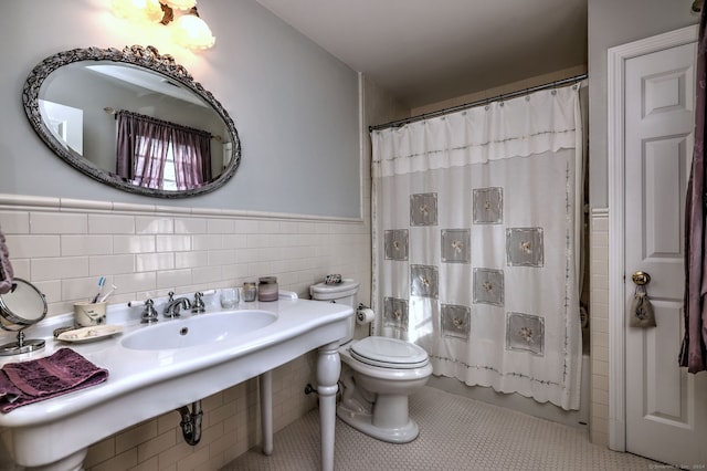 full bathroom with tile patterned floors, toilet, sink, tile walls, and shower / bathtub combination with curtain