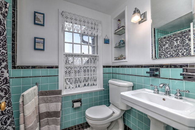 bathroom featuring toilet, sink, and tile walls