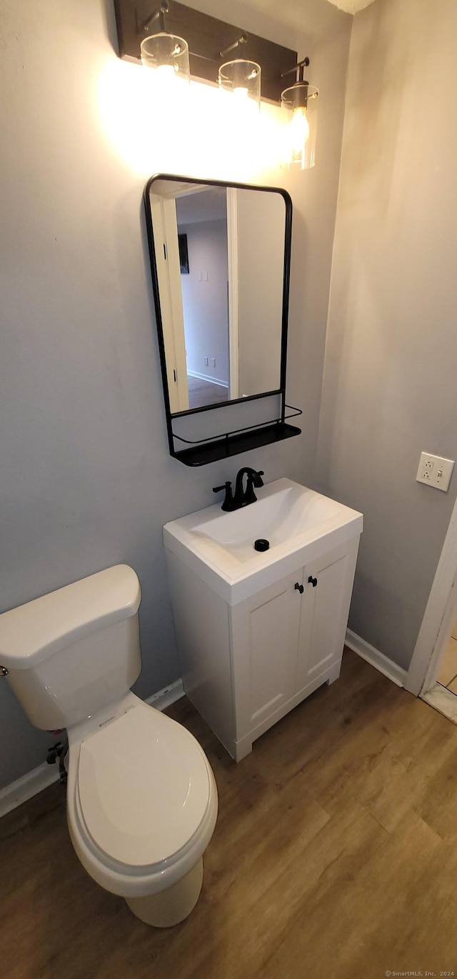 bathroom with toilet, vanity, and hardwood / wood-style flooring