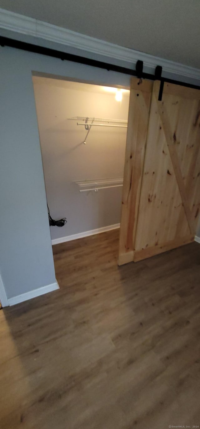 interior space featuring a barn door, crown molding, and wood-type flooring