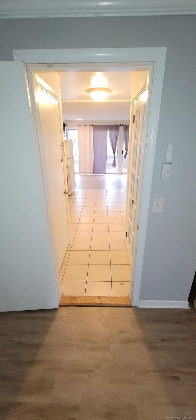 hallway with ornamental molding and light tile patterned flooring