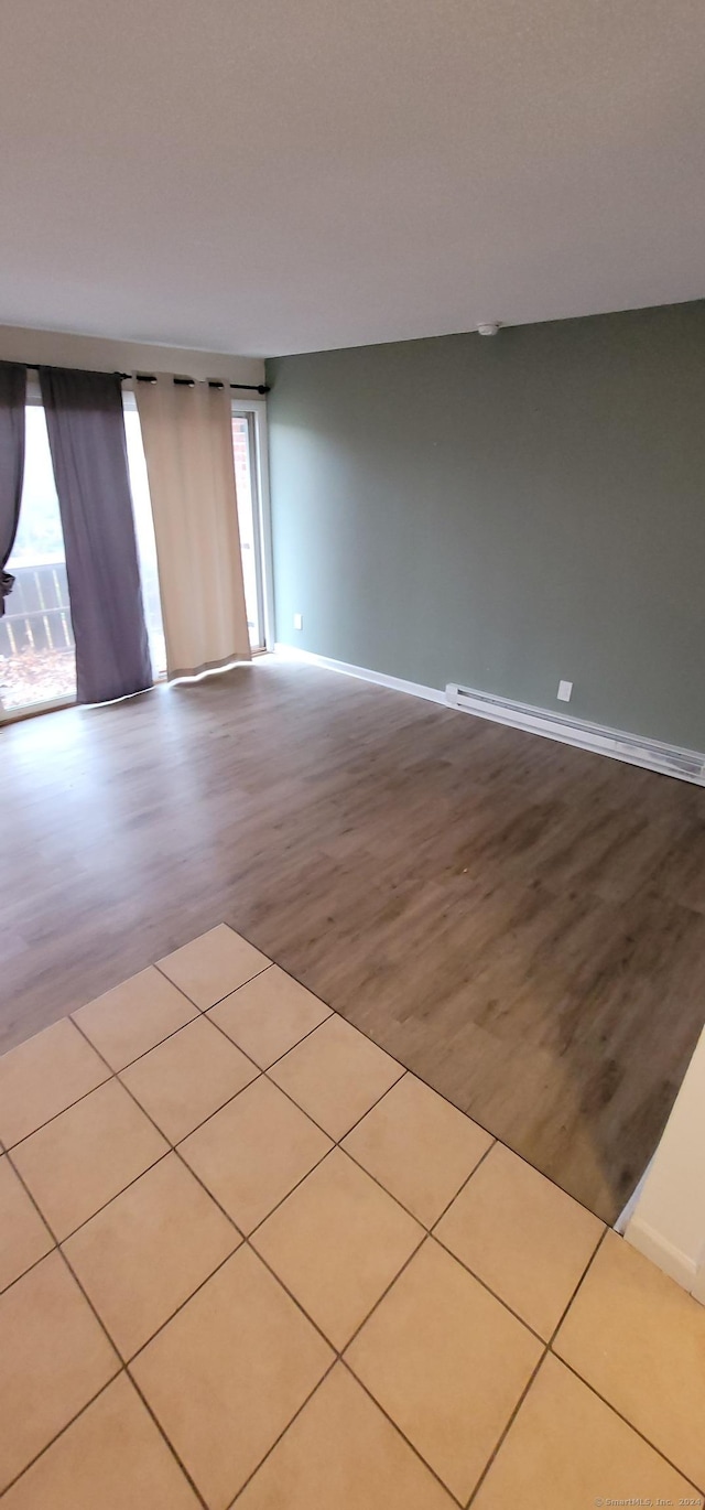 empty room featuring light hardwood / wood-style flooring, baseboard heating, and a healthy amount of sunlight