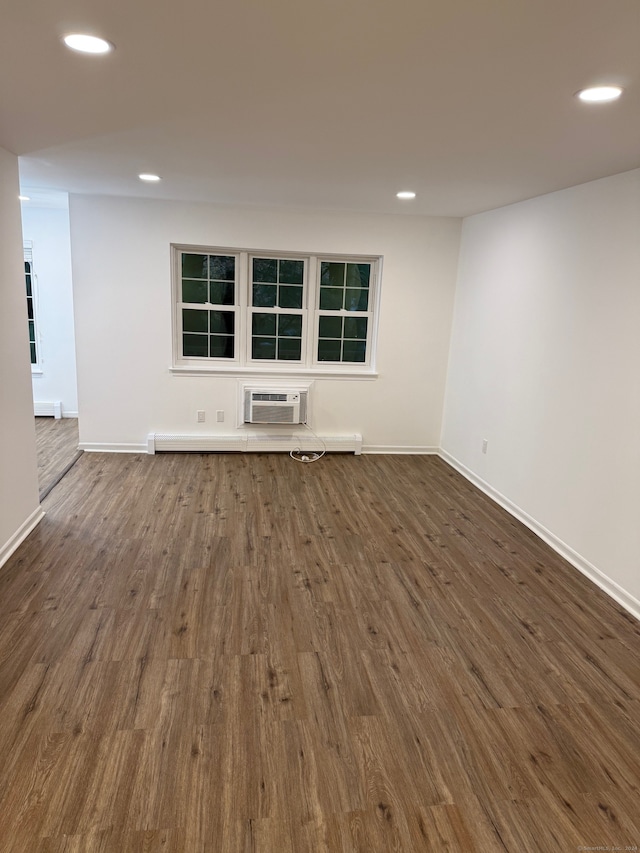 empty room featuring an AC wall unit, baseboard heating, and dark hardwood / wood-style floors