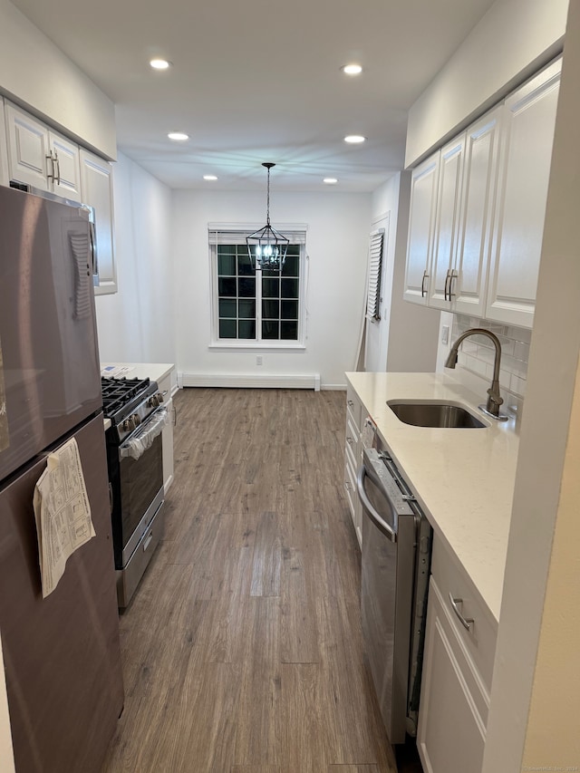 kitchen with stainless steel appliances, pendant lighting, hardwood / wood-style floors, sink, and white cabinets