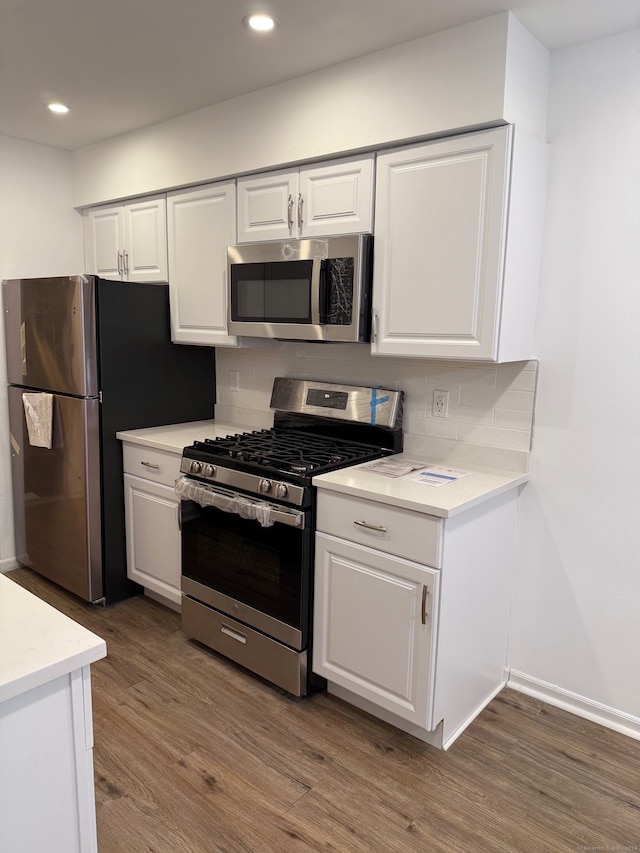 kitchen with stainless steel appliances, white cabinetry, and dark wood-type flooring