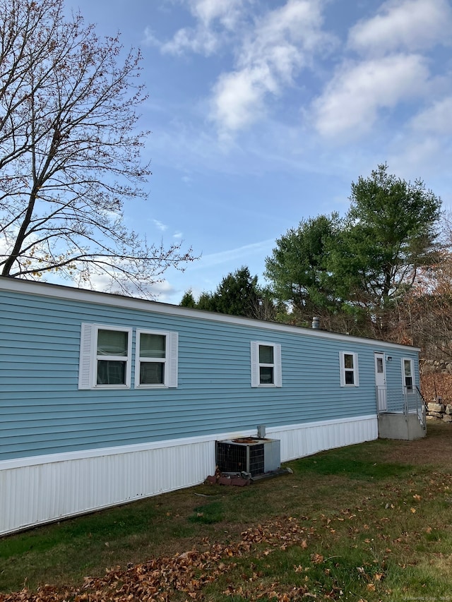 view of side of home with a lawn and cooling unit