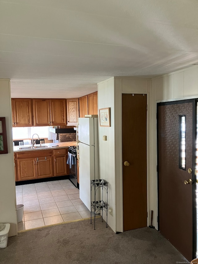 kitchen with black / electric stove, sink, light carpet, and white fridge