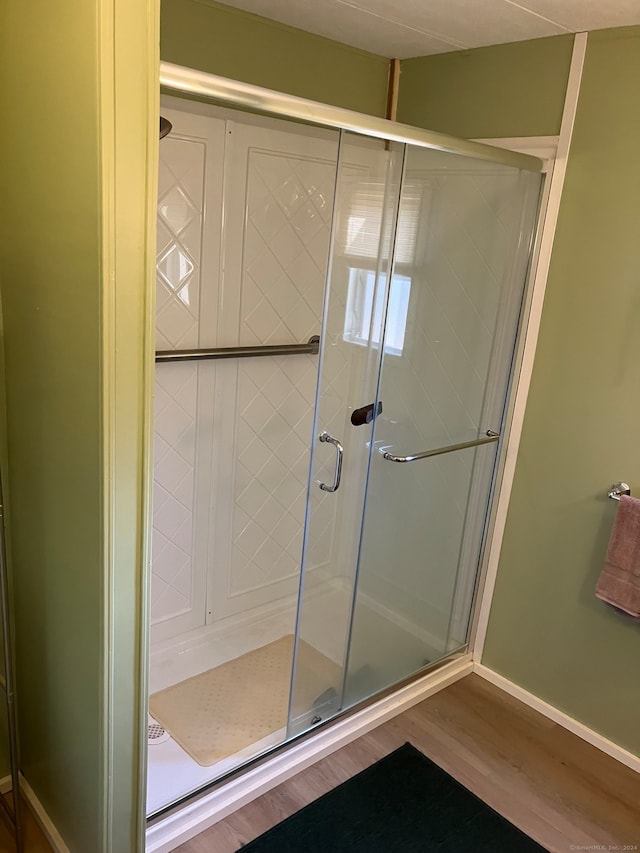 bathroom with an enclosed shower and wood-type flooring